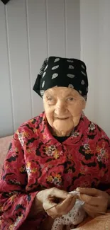 Elderly woman in vibrant floral clothing, smiling peacefully at home.