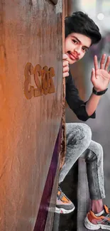 Young man waving from a train carriage in an urban setting.