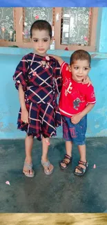 Two children in bright outfits near the ocean on a tropical beach.