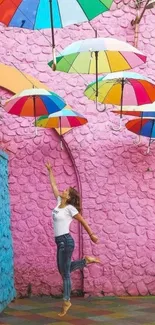 Woman jumping under colorful umbrellas in a vibrant alley.