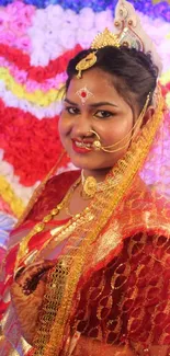 A woman in red traditional wedding attire with floral backdrop.