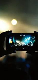 Hands holding phone capturing a live concert scene.