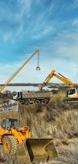 Yellow construction vehicles on coastal landscape under blue sky.