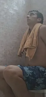 Person sitting in a shower with a towel draped over shoulders, deep in thought.