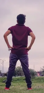 Person stands thoughtfully in urban landscape with sky backdrop.