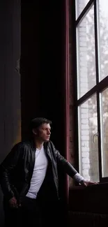 Man gazing out a large window, reflective mood.