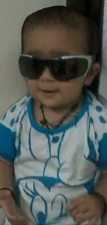 Cute baby wearing sunglasses and a blue shirt.