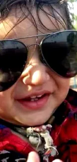 Happy baby wearing sunglasses with a red outfit.