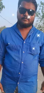 Man in blue shirt with sunglasses, outdoor setting.