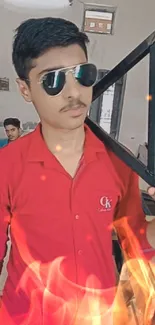 Stylish young man in red shirt with sunglasses, framed by flames.