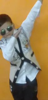 Stylish kid in sunglasses dabbing against an orange background.