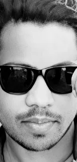 A stylish monochrome portrait of a person wearing sunglasses, set against a textured background.