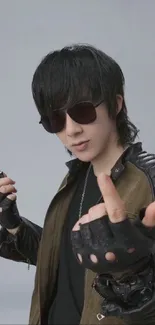 Mysterious person in sunglasses and leather attire with a gray background.