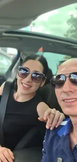 Couple enjoying a car selfie with sunglasses on a sunny day.