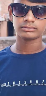 Young person wearing sunglasses and navy blue t-shirt.