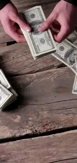 Hands counting dollar bills on rustic wooden table.