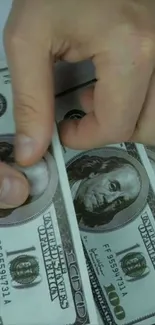 Hands counting hundred dollar bills, close-up view.