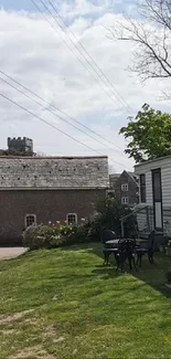 Countryside view with a stone building and caravan under a blue sky.