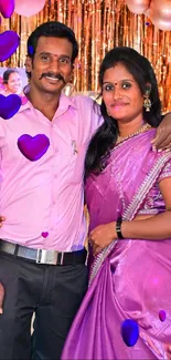 Couple in traditional attire with heart-shaped balloons and festive background.