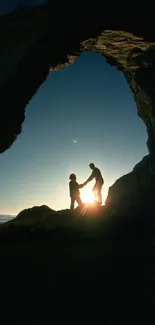 Silhouette of a couple at sunset framed by a natural archway on the beach.