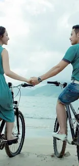 Couple biking by the beach, holding hands.