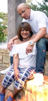 Couple sitting together in urban setting with stone backdrop.