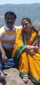 Couple in traditional attire with mountain backdrop.