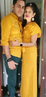 Couple in matching yellow outfits by a window.