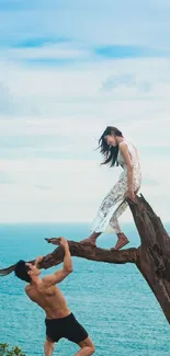 Couple on tree over ocean in scenic wallpaper.