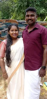 Couple in traditional attire outdoors surrounded by nature.