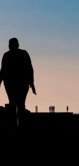 Silhouette of a couple at sunset, hand in hand, against a calm sky backdrop.