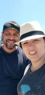 Smiling couple under bright blue sky.