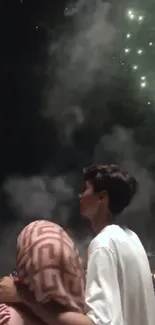 Couple watching fireworks in night sky.