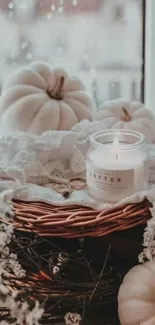 Cozy autumn scene with candles, pumpkins, and lace on a windowsill.