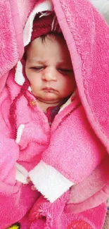 Adorable baby sleeping wrapped in a pink blanket.