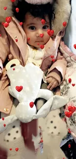 Cute baby in pink coat with heart motifs, ideal for mobile wallpaper.