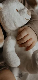 Baby holding plush bunny in cozy setting.