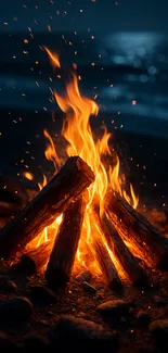 A glowing bonfire on a beach at night by the ocean.