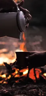 Hands pour coffee by a warm campfire.