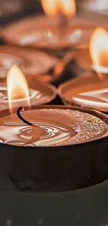 Close-up of flickering candles with warm orange glow.