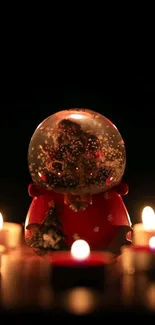 Snow globe surrounded by warm candles in a cozy setting.