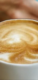 Close-up of cappuccino with swirling latte art in a white cup.