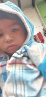 Young child in a cozy blue hoodie, looking thoughtful.