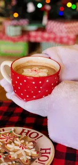 Santa holding a red mug of hot cocoa with festive Christmas cookies.