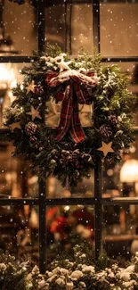 Festive window with Christmas wreath and snowfall.
