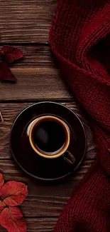 A cozy scene with coffee, red leaves, and a scarf on wooden background.
