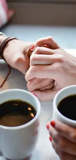 Two hands holding with coffee mugs on table.