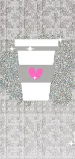 A coffee cup with glitter heart on a knitted gray background.