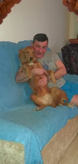 Man with dog on blue couch with brick frame.