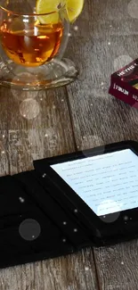 Cozy setup with eBook reader, books, tea, and spectacles on a wooden table.